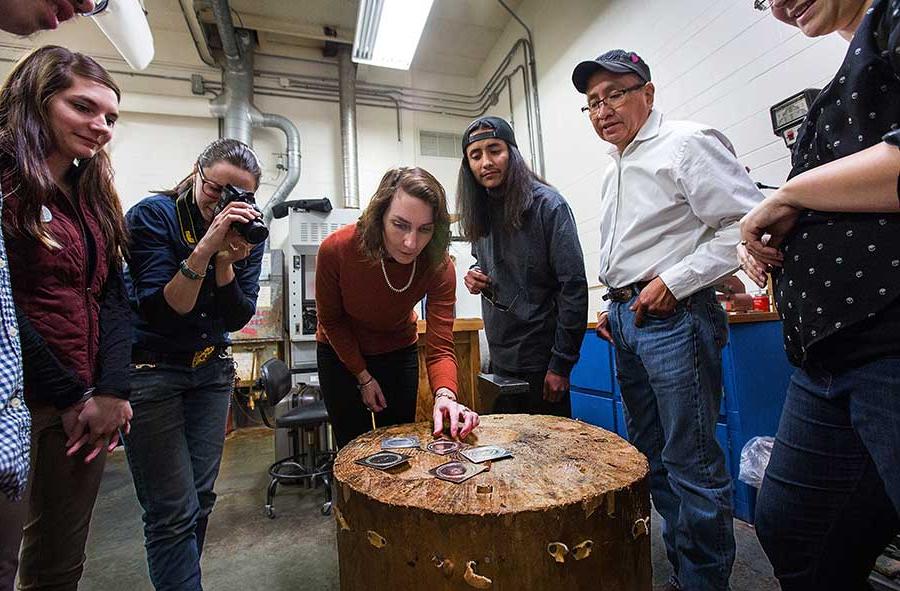 Teresa Faris sits on a table in a jewelry lab.