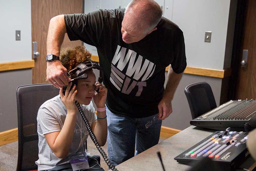 Jim Mead helps a CyberGirlz camper with a headset in the control room.