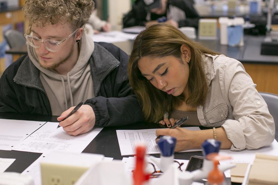 Two students work at a desk.